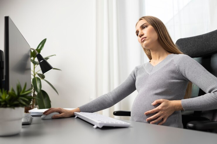 side view pregnant businesswoman her desk holding her belly